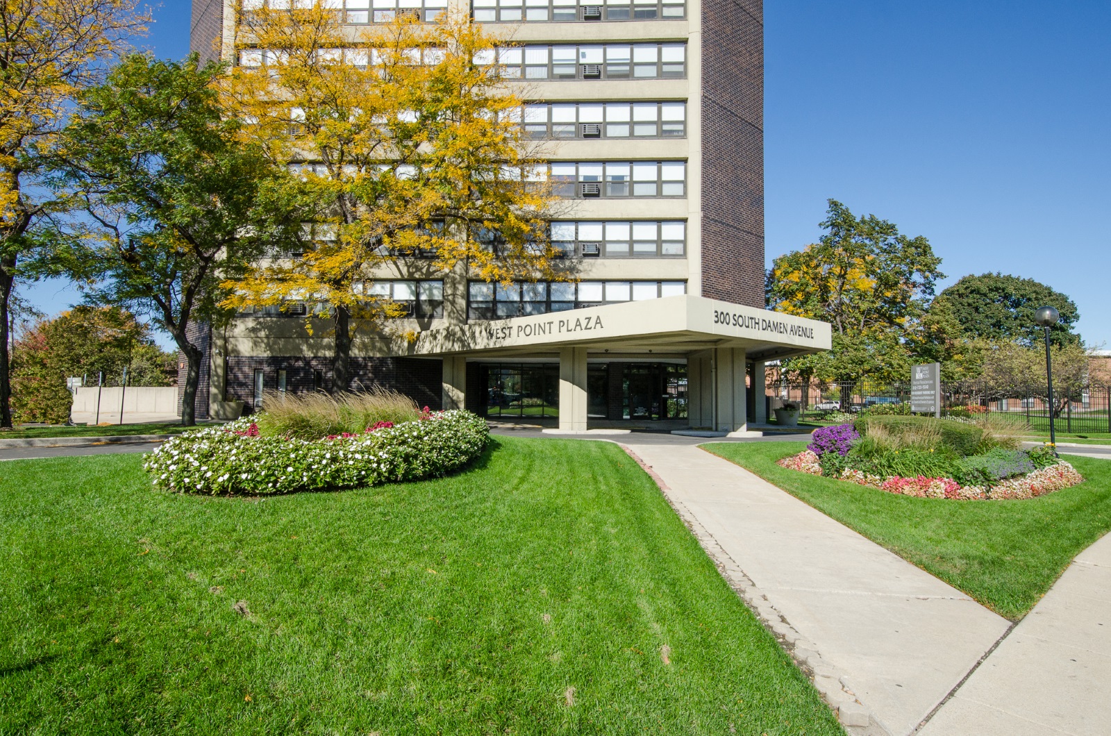 the front of a building with a green lawn and flowers
